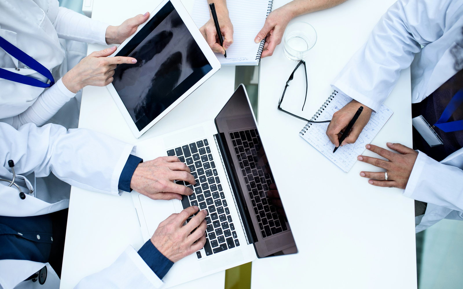 Clinicians reviewing a scan on a tablet around a table with a laptop and notes
